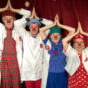 Fyra clowner med händerna ovanför huvudena i form av ljus
